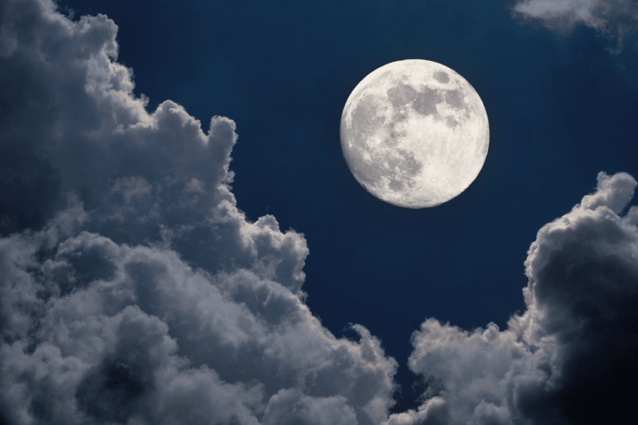 Luna llena brillante entre nubes oscuras en el cielo nocturno, simbolizando los ciclos lunares y su energía transformadora.